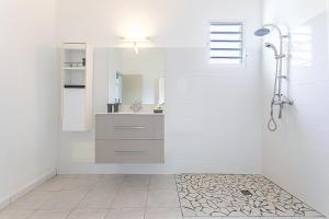 un bagno bianco con lavandino e doccia di Thijo Guadeloupe a Baie-Mahault