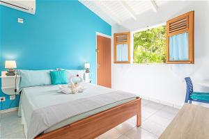 una camera da letto con un letto con pareti blu e una finestra di Thijo Guadeloupe a Baie-Mahault