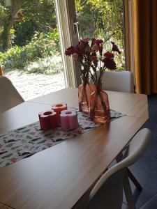 a wooden table with flowers and two candles on it at B&B de Loeff in Waalwijk