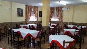 a dining room with tables and chairs with red bows at Hostal Rural Venta La Vega in Ronda