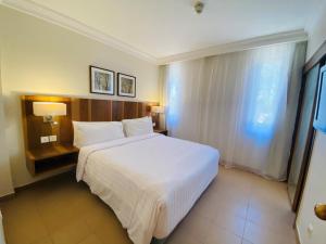 Un dormitorio con una gran cama blanca y una ventana en Hurghada Suites & Apartments Serviced by Marriott, en Hurghada