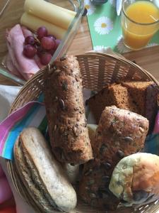 una cesta de pan, queso, uvas y un vaso de zumo de naranja en B&B de Loeff, en Waalwijk
