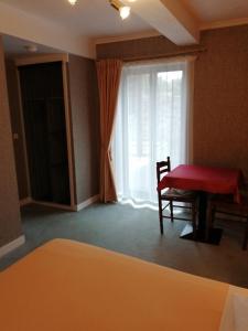 a room with a red table and a chair and a window at Le casse noisettes in Gourin