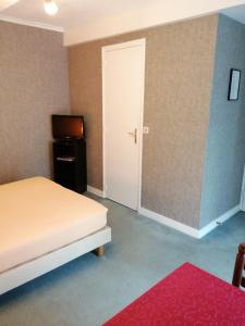 a bedroom with a bed and a television and a door at Le casse noisettes in Gourin