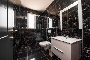 a black tiled bathroom with a toilet and a sink at David Lux beach rooms in Dobra Voda