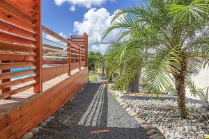 a fence and two palm trees in a yard at Thijo Guadeloupe in Baie-Mahault