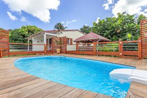 a swimming pool with a wooden deck and a house at Thijo Guadeloupe in Baie-Mahault