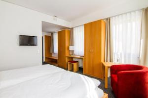 Habitación de hotel con cama y silla roja en Energiehotel Kultiviert en Wildpoldsried