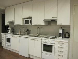 a white kitchen with white cabinets and appliances at Finn Rooms in Tampere