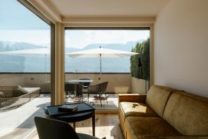 - un salon avec un canapé et une table avec un parasol dans l'établissement Ansitz am Eck by Hotel Pernhof, à Termeno