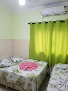 two beds in a room with a green curtain at Hotel Luz do Sol in Aparecida