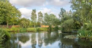 a river in a park with trees and bushes at "George's" lakeside wooden tipi in Sudbury