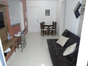 a living room with a black couch and a table at Apartamento em Mongaguá, Frente ao Mar in Mongaguá