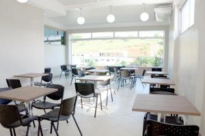 a cafeteria with tables and chairs and a large window at Hotel Golden JK in Muriaé