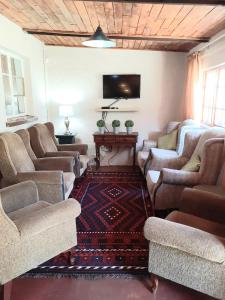 ein Wohnzimmer mit Sofas und einem Flachbildfernseher in der Unterkunft Skye High House & Cottage in Dullstroom