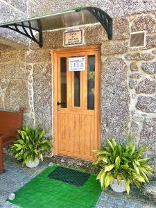 una porta in legno su un edificio in pietra con piante di Casa da Quinta da Prelada Simão partie basse a Celorico de Basto