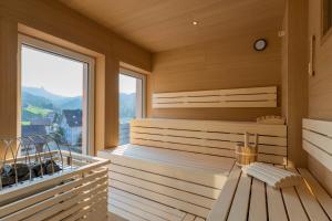 a sauna with a bench and a large window at Roggenstock Lodge in Oberiberg