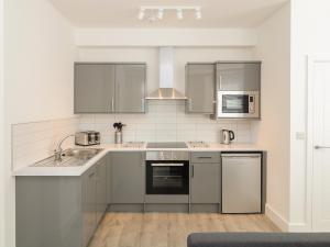 uma cozinha com electrodomésticos de aço inoxidável e armários cinzentos em Samphire em Teignmouth