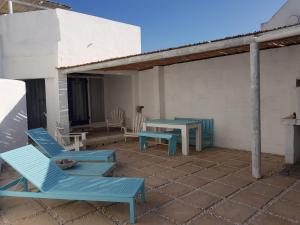 a patio with two blue chairs and a table at Mosselbank Beach Retreat 2A in Paternoster