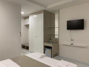 曼谷的住宿－Icare Residence & Hotel，白色的房间,墙上配有电视