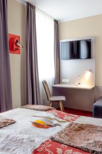 Schlafzimmer mit einem Bett, einem Schreibtisch und einem Fenster in der Unterkunft Hotel zum Fischer in Dachau
