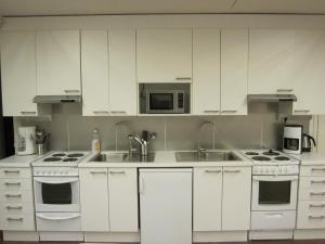 タンペレにあるFinn Roomsの白いキャビネット、シンク、電子レンジ付きのキッチンが備わります。