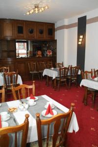 Hotel Jägerhalle في Falkenstein: غرفة طعام بطاولات بيضاء وكراسي خشبية