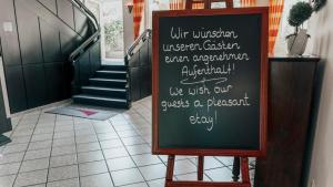 a chalkboard sign in a hallway with a staircase at Avantgarde Hotel in Hattingen