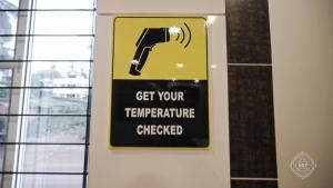 a sign on a wall that says get your temperature checked at Hotel Rahul Palace Belgaum in Belgaum +33 photos
