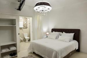 a bedroom with a large white bed and a chandelier at Ivlas Boutique Hotel in Santa Maria