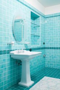 ein blau gefliestes Bad mit einem Waschbecken und einem Spiegel in der Unterkunft Agriturismo Gazza Ladra in Noventa di Piave
