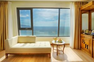 a living room with a white couch and a large window at Serene Beach Danang Hotel in Danang