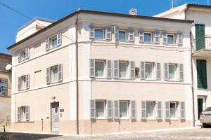 un edificio bianco con finestre con persiane bianche di Marinelli Apartments - La Madonnina a Osimo