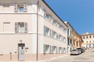 un edificio bianco con un'auto parcheggiata di fronte di Marinelli Apartments - La Madonnina a Osimo