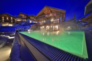 una casa con piscina por la noche en Mountains Hotel, en Seefeld in Tirol