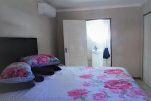 a bedroom with a bed with pink flowers on it at Sunrise Cottage in Upington