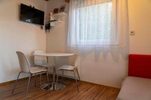 ein kleines Zimmer mit einem Tisch, Stühlen und einem Fenster in der Unterkunft Apartma Vražič in Bled