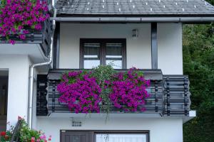 a white house with pink flowers on a balcony at Apartma Vražič in Bled