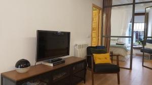a living room with a flat screen tv and a chair at Murallas de Sigüenza in Sigüenza