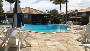 a swimming pool with chairs and an umbrella at CASA EM ÓTIMO CONDOMINIO DE BUZIOS in Búzios