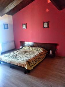a bedroom with a bed in a red wall at La casa de Jesús Llandres in Husillos