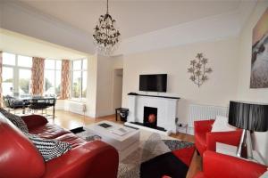 a living room with a red couch and a fireplace at Rosemorran Holiday Apartments in St Ives