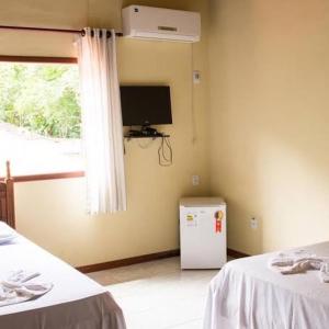 a room with a small refrigerator and a window at Pousada Nativa in Paraty