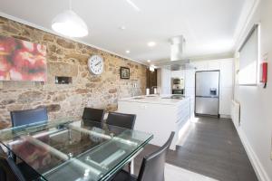 Una cocina y un comedor con una mesa de cristal. en Quinta da Devesa, en Valença