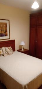 a bedroom with a large white bed and a lamp at Apartamento gramado RS centro in Gramado