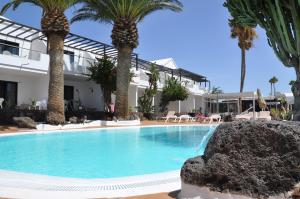 a swimming pool in front of a house with palm trees at Los Tulipanes in Puerto del Carmen