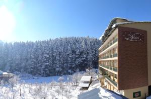 un hotel con árboles nevados en el fondo en The Orchard Greens Resort - A Centrally Heated Property en Manāli