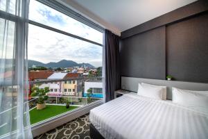 a hotel room with a bed and a large window at Deview Hotel Penang in Ayer Itam