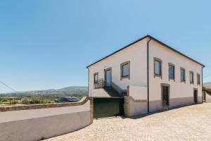 um grande edifcio branco com uma garagem ao lado em Casa de Lagarinhos JACUZZI SPA JOGOS GYM - SERRA DA ESTRELA - SEIA - GOUVEIA em Gouveia
