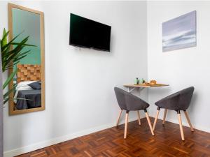 a room with two chairs and a television on a wall at Nartè Rooms in Naples